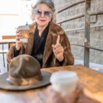 woman in brown coat sitting beside brown wooden table